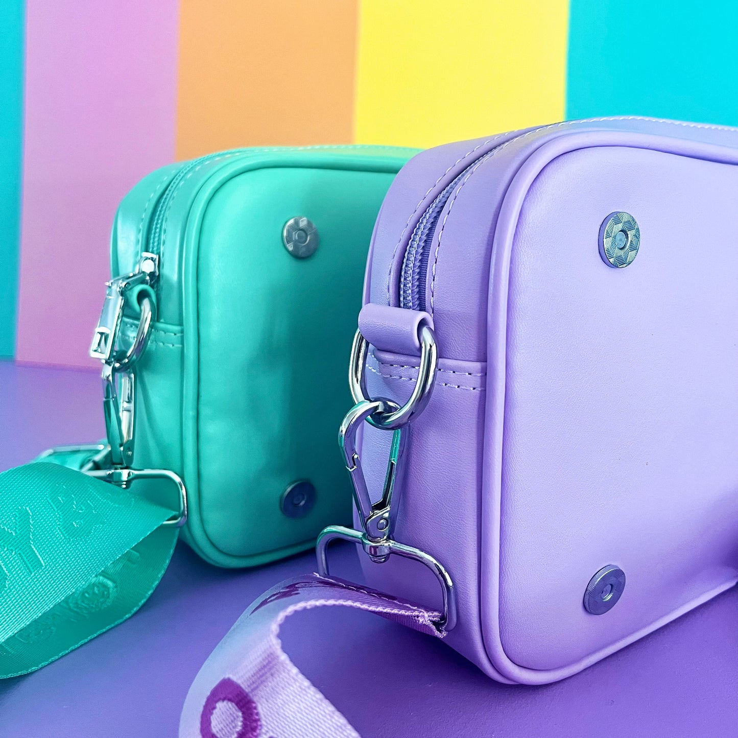 Kids crossbody bags from Popsy and Co. It shows the side view of the mint and purple bags. The bags have magnetic clips on the front for kids to easily attach a Popsy interchangeable cover.