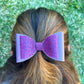 Purple glitter hair bow in girls hair.