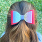 Red and rainbow glitter hair bow in girls hair.