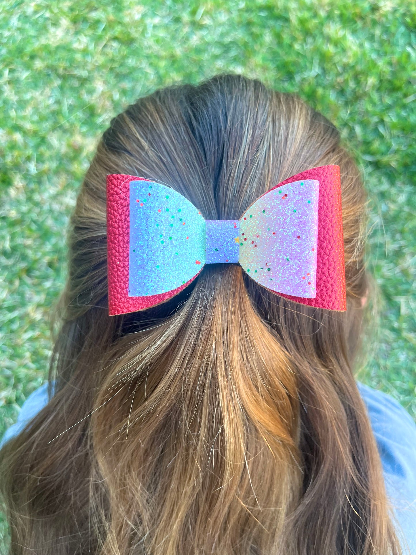 Red and rainbow glitter hair bow in girls hair.