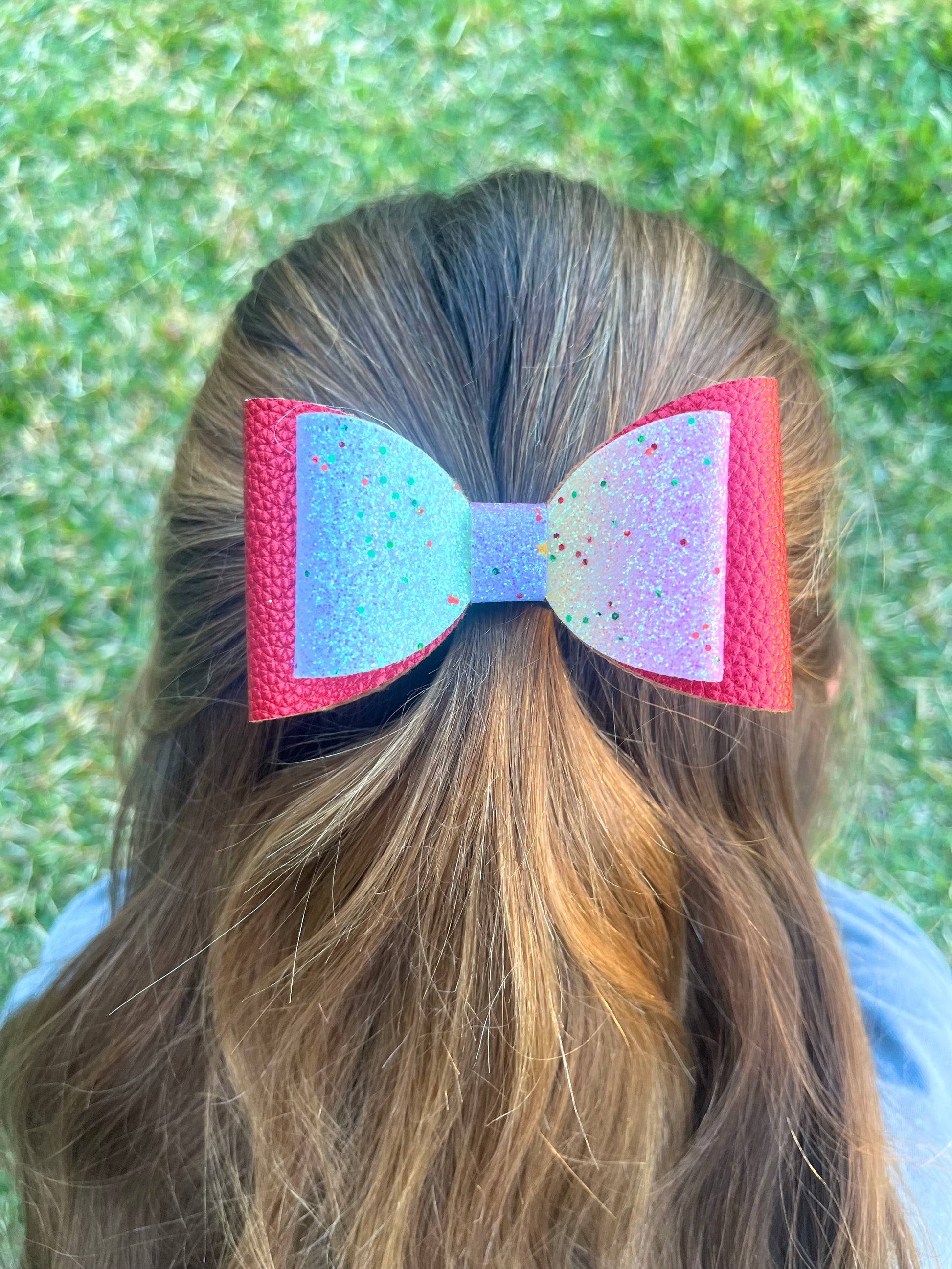 Red and rainbow glitter hair bow in girls hair.