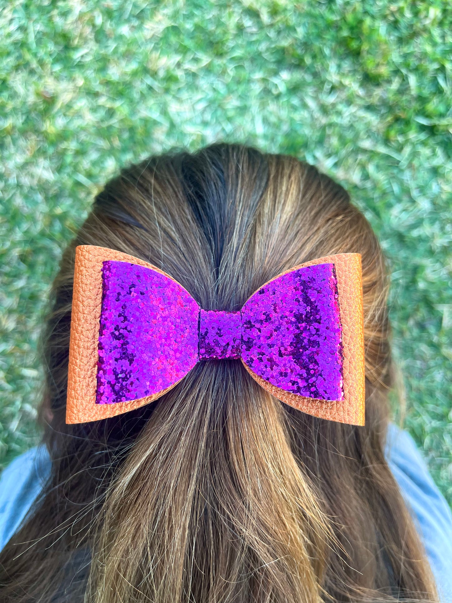 Orange and pink glitter hair bow in girls hair.