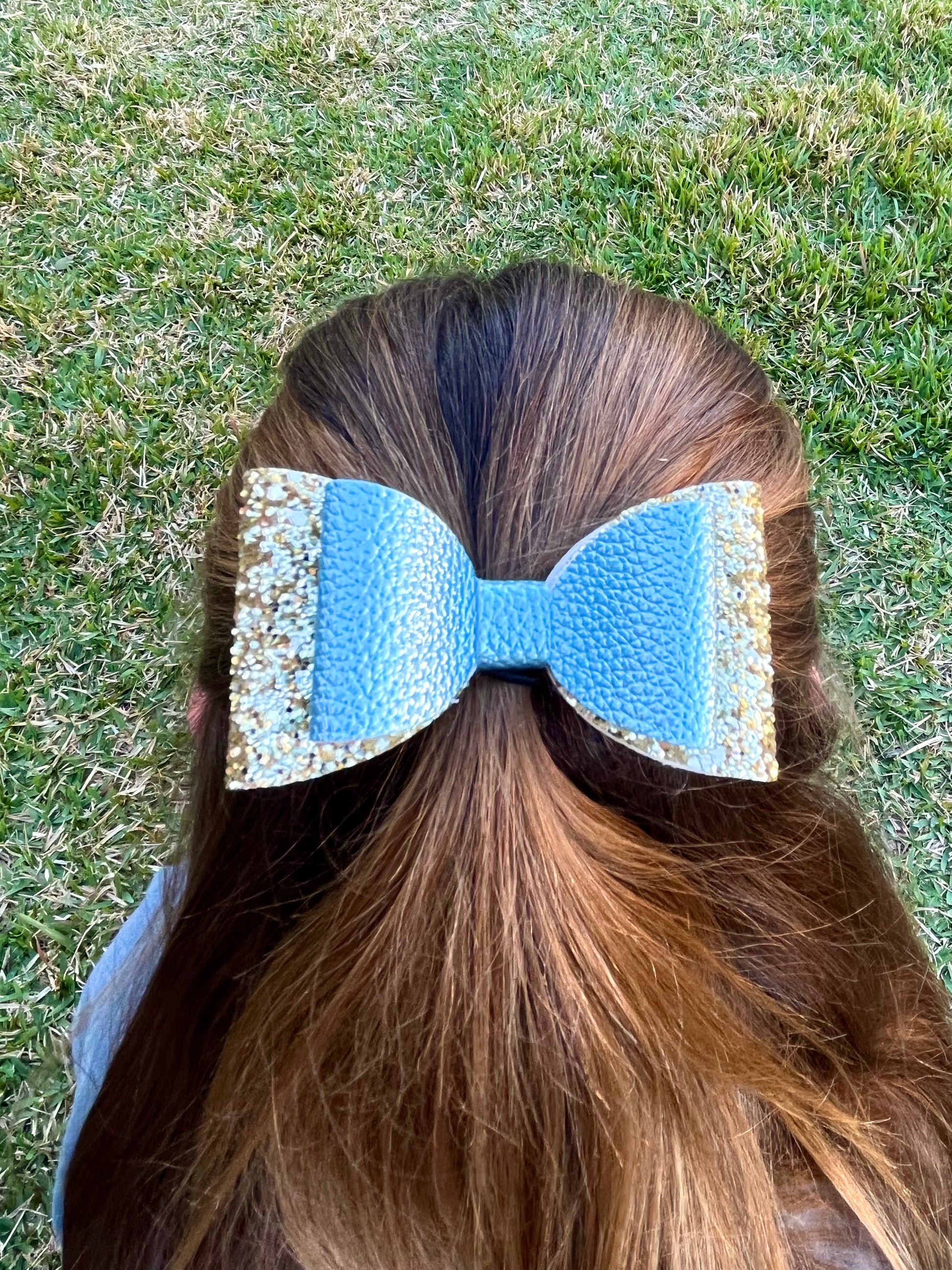 Blue and gold glitter hair bow in girls hair.