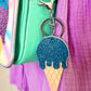 Blue glitter icecream bag charm. It is clipped onto a Popsy & Co crossbody bag with a silver-like clip.