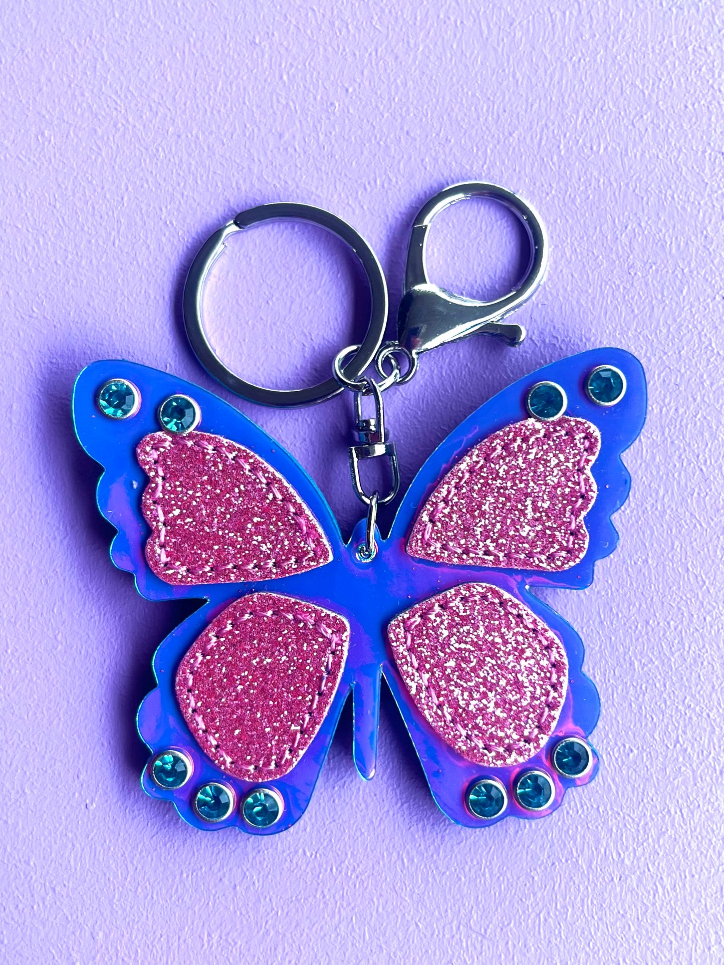 Butterfly accessory keyring for kids. It has glitter and blue gems.