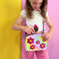 Girl wearing a kids purple crossbody bag with the Flower Fields interchangeable cover from Popsy and Co.