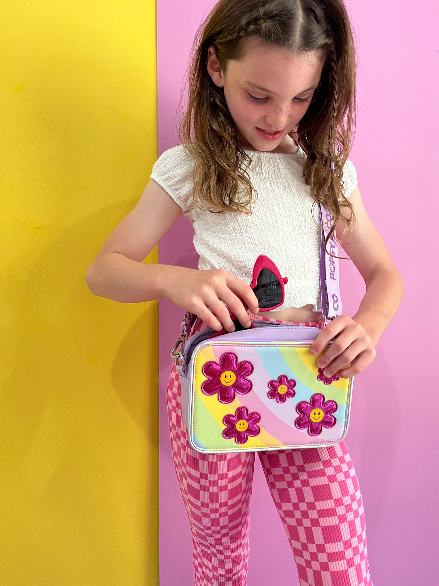 Girl wearing a kids purple crossbody bag with the Flower Fields interchangeable cover from Popsy and Co.