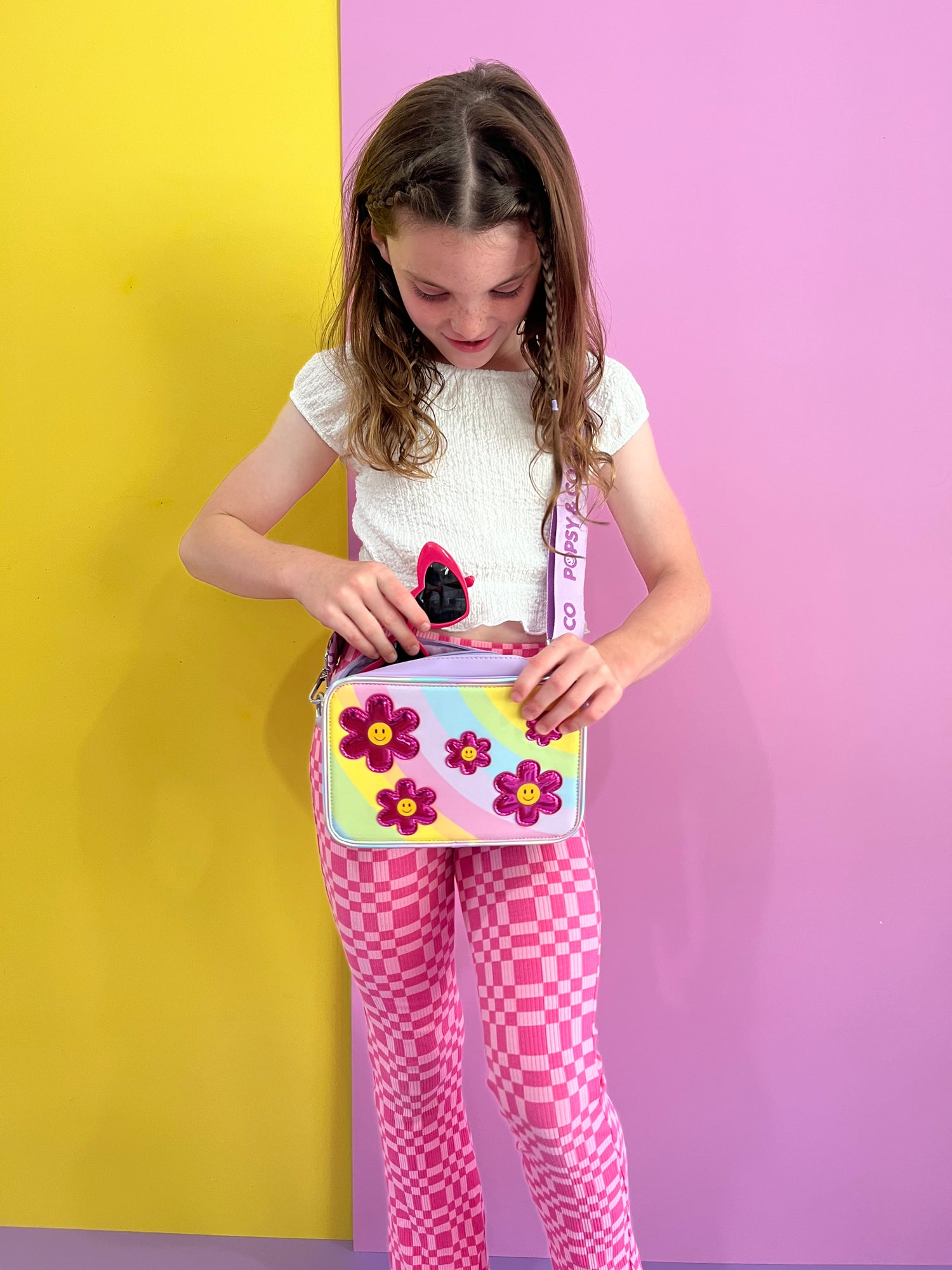 Girl wearing a kids purple crossbody bag with the Flower Fields interchangeable cover from Popsy and Co.